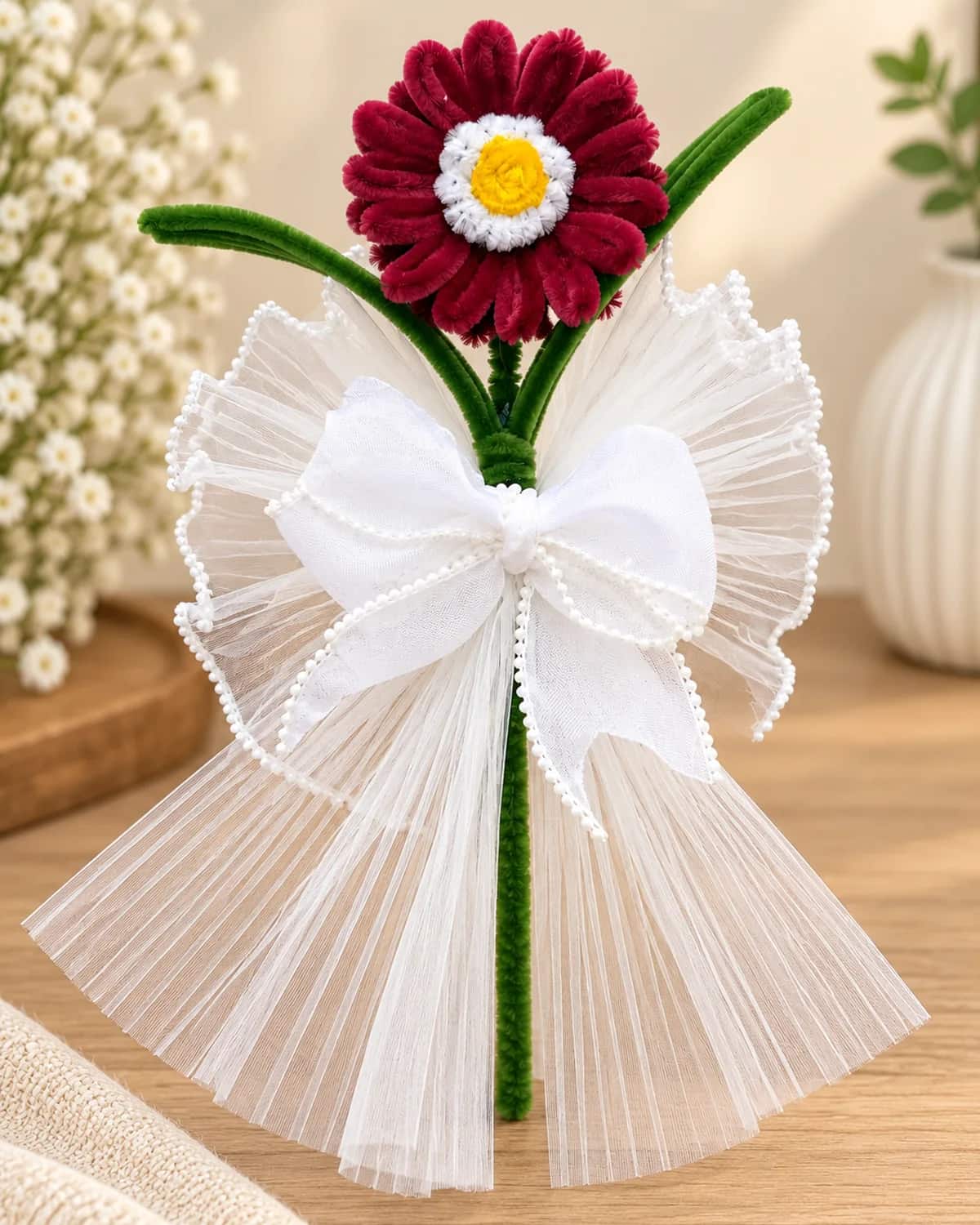 single handmade chenille flower on a long wrapped stem, in a pleated tulle wrap with a pearl-edged bow